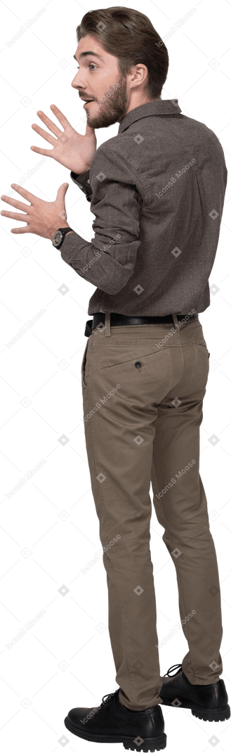 Three-quarter back view of an emotional gesticulating young man in office clothing