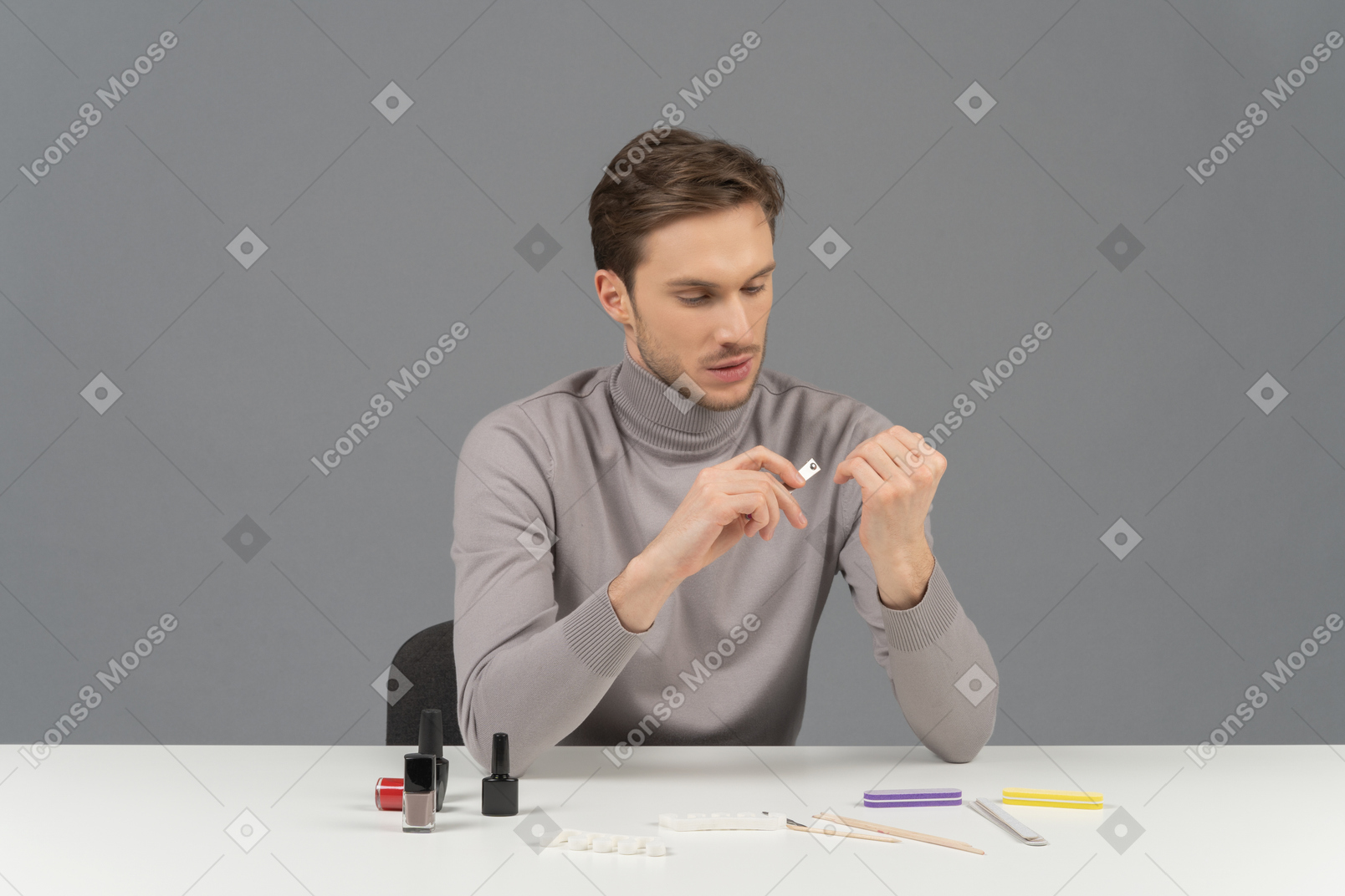 A young man attentively arranging his nails