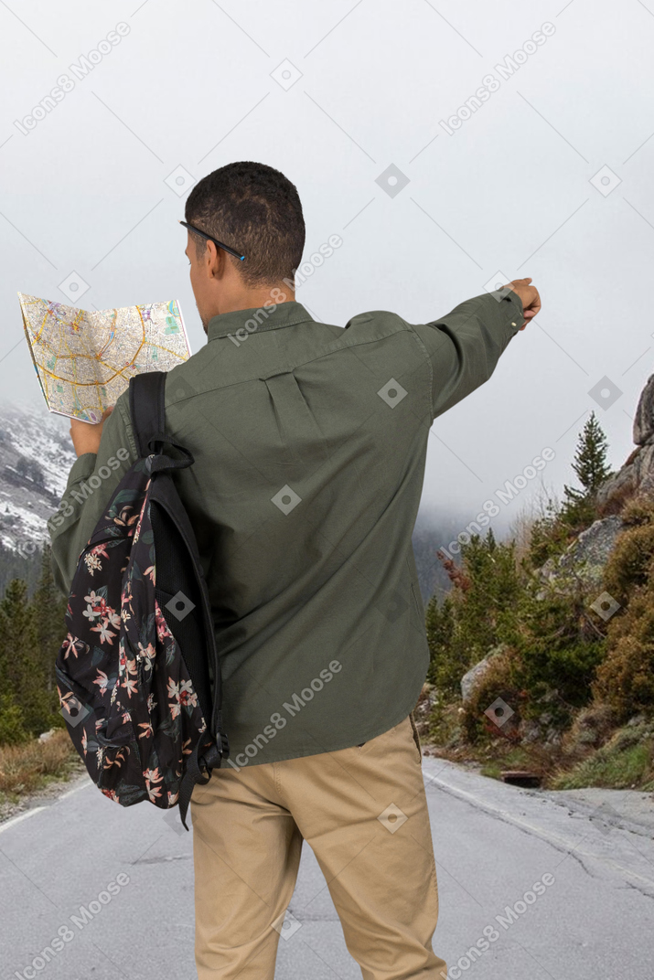 A man with a backpack looking at a map