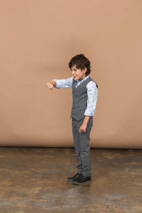 Side view of a boy in grey suit showing thumb down