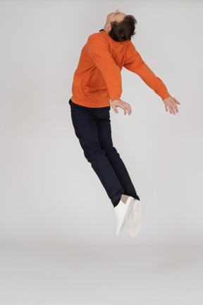 Junger mann im orange sweatshirt springen