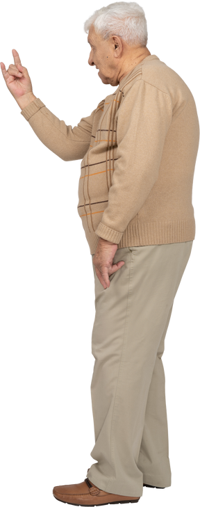 Vista laterale di un uomo anziano in abiti casual che mostra un gesto rock