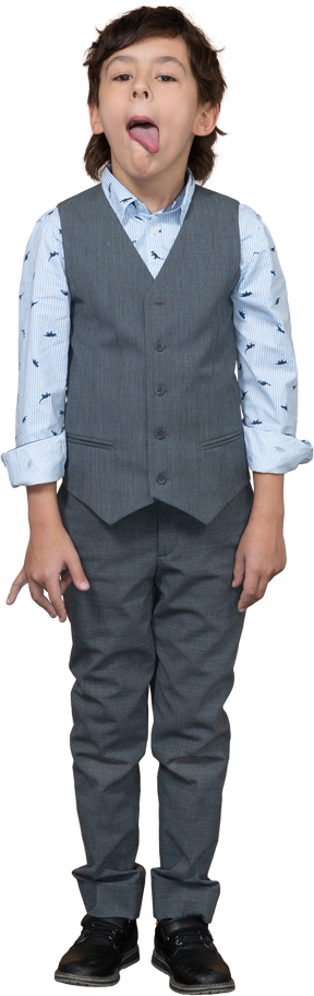 Вид спереди симпатичного мальчика в сером костюме, показывающего язык