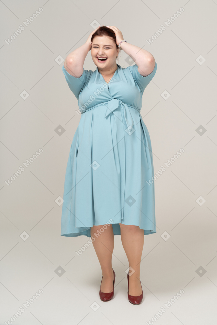 Front view of a happy woman in blue dress touching head