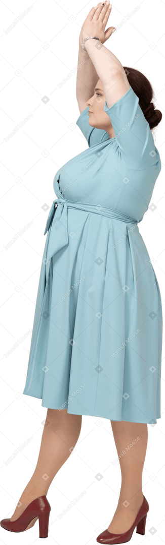 一个穿着蓝色连衣裙的女人做祈祷手势的侧视图