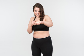 Smiling young plus-size woman standing in fighting stance