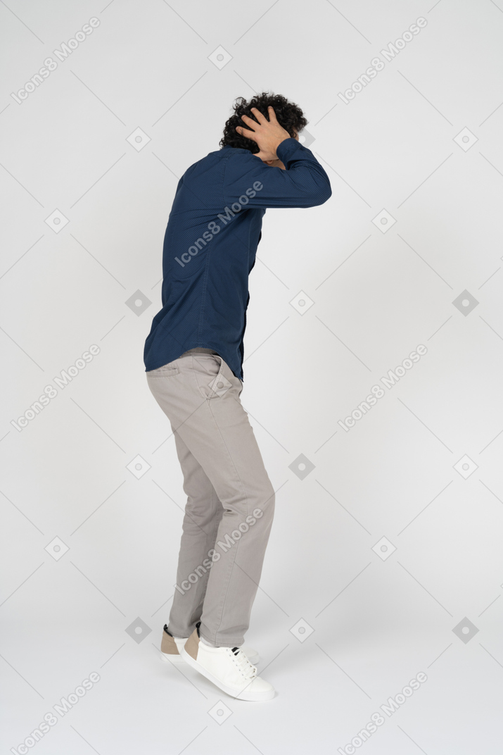 Vista lateral de um homem com roupas casuais tocando a cabeça