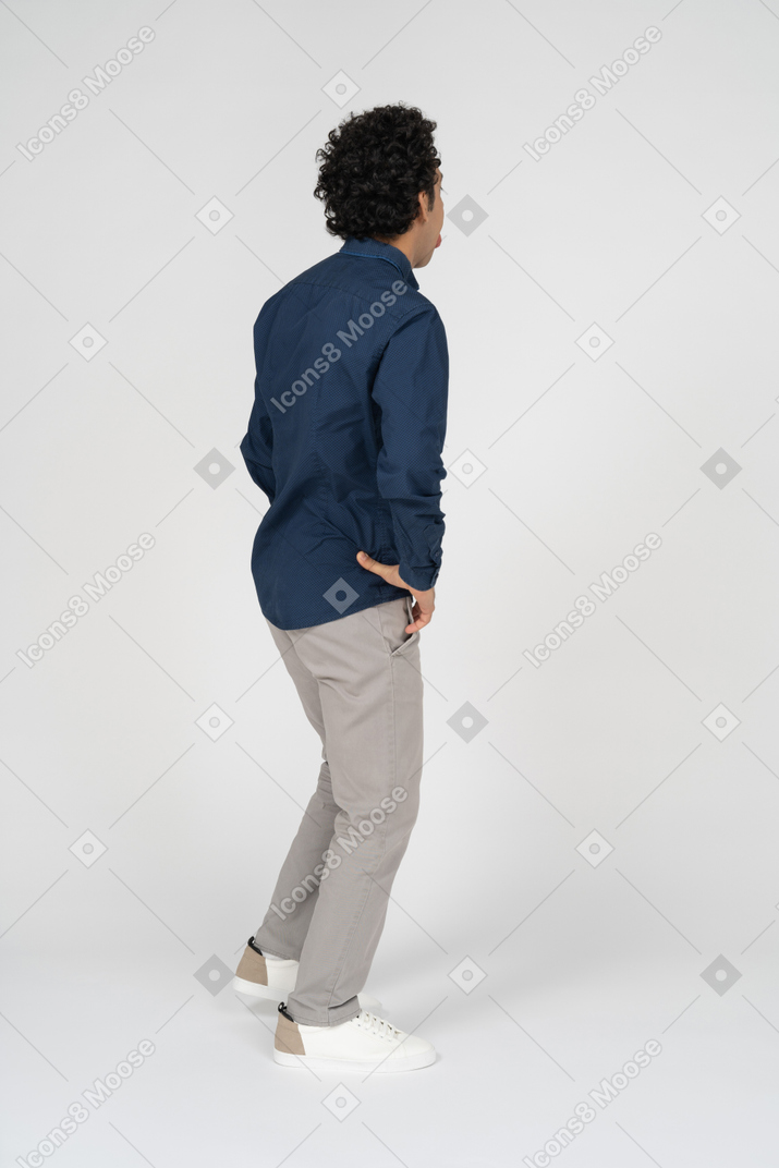 腰に手を置いて立っているカジュアルな服を着た男の側面図