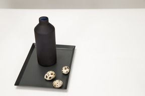 Black vase and quail eggs on the black tray