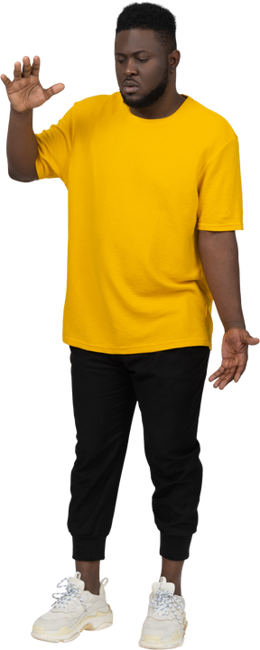 一个身穿黄色 t 恤的黑皮肤年轻男子的前视图，显示某物的大小