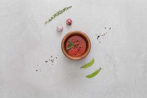 A bowl of gazpacho, some garlic, green peas