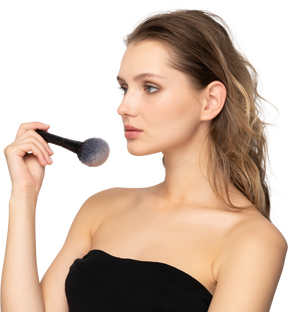 Three-quarter view of a sensual young woman holding a make-up brush
