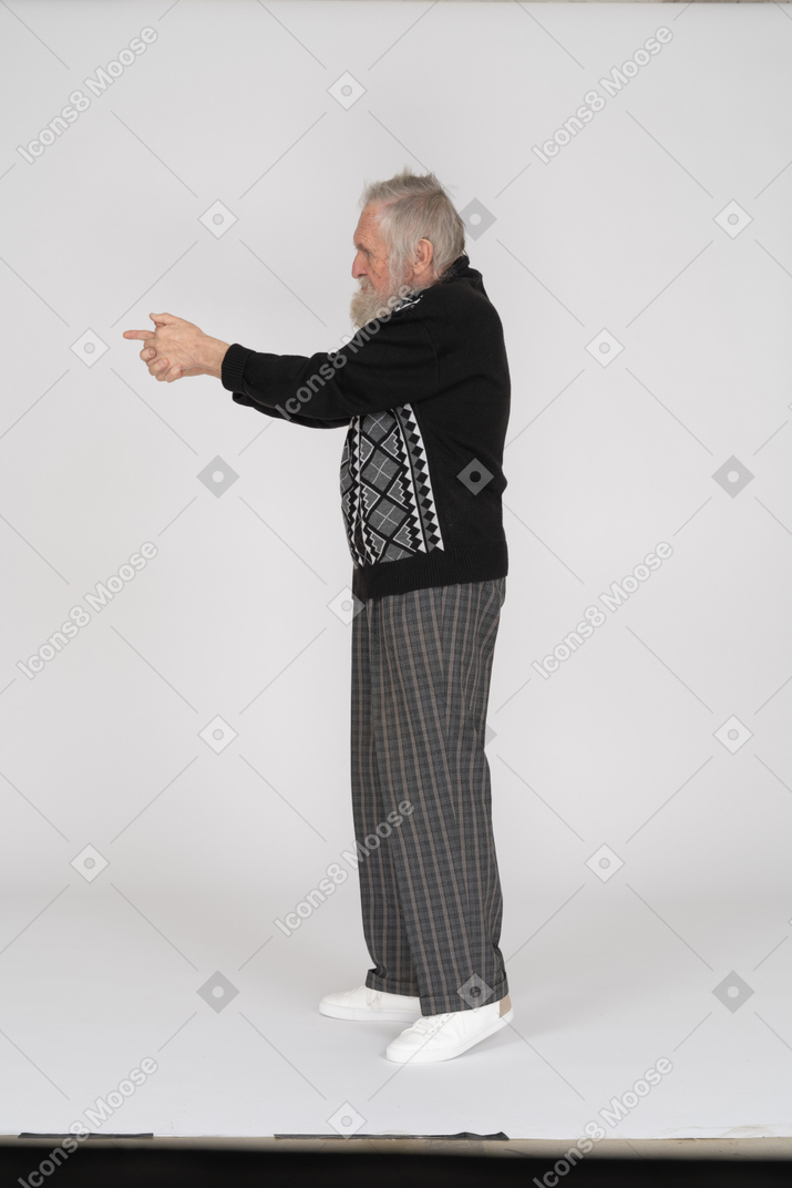 Vista lateral del anciano apuntando con pistola de dedo