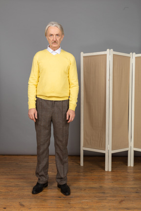 Front view of an old man standing still by the screen