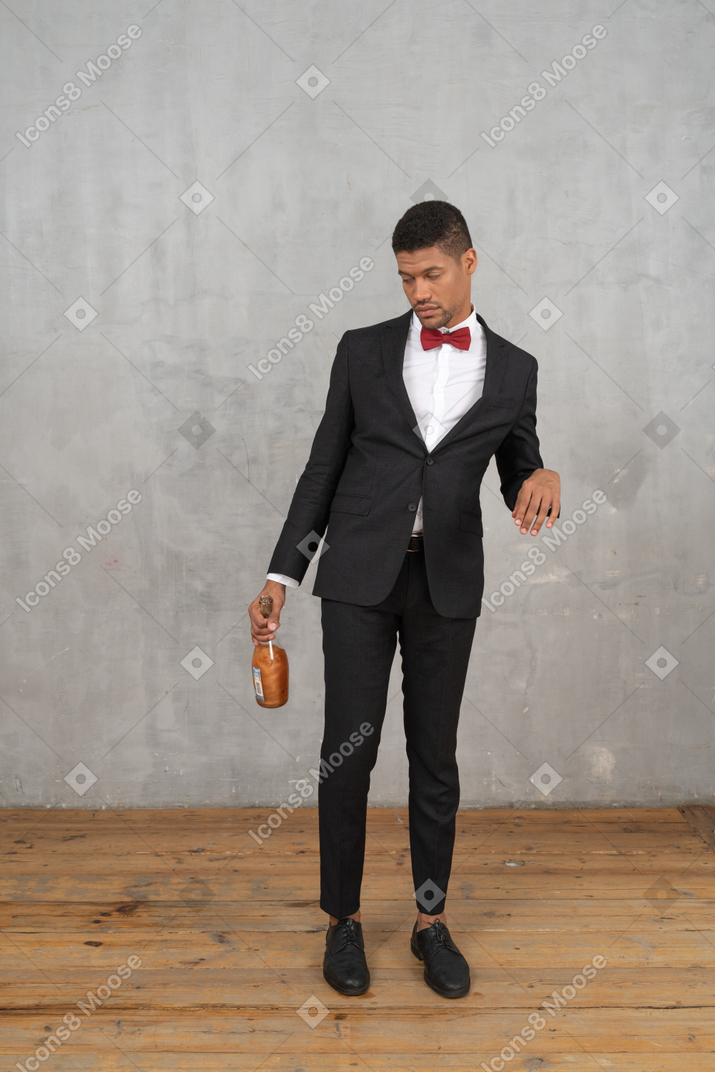 Jeune homme avec une bouteille à la main regardant vers le bas