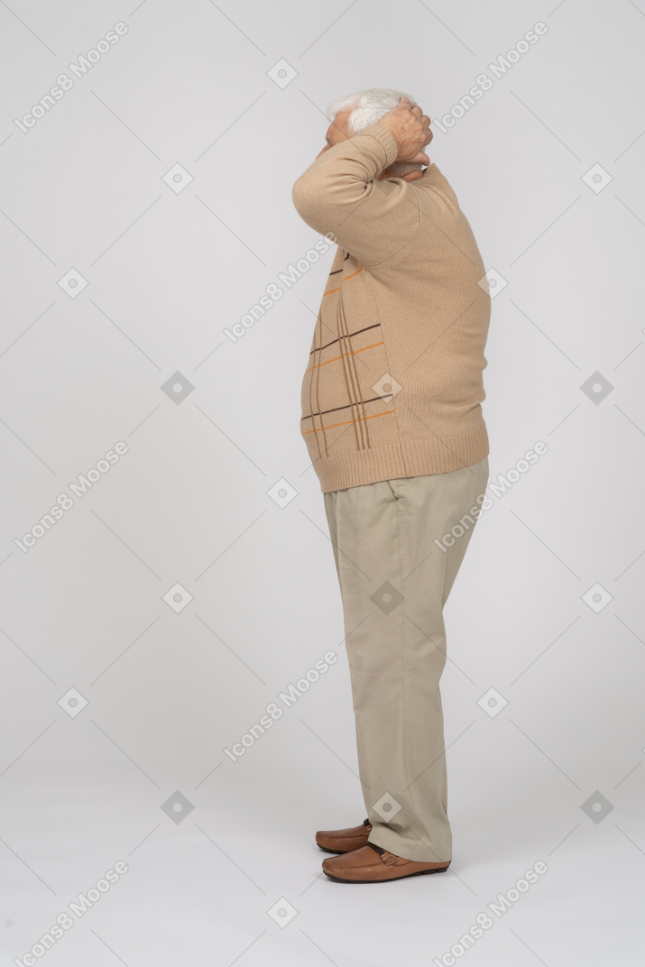 Vue latérale d'un vieil homme en vêtements décontractés debout avec les mains derrière la tête