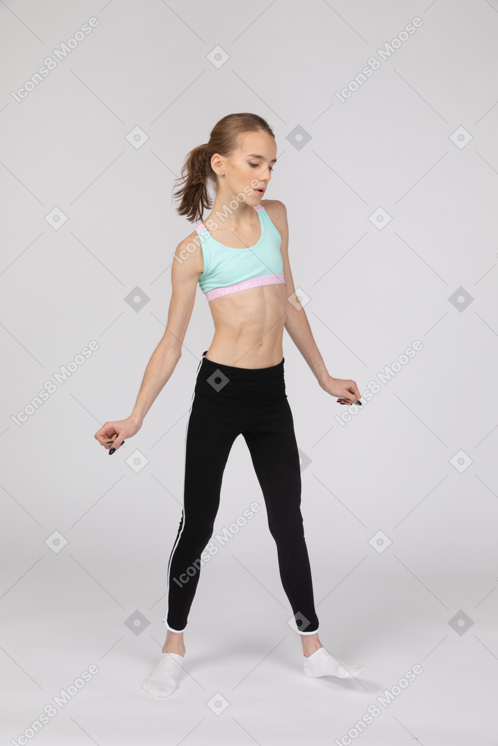 Vista frontal de una jovencita en ropa deportiva mirando a la cámara