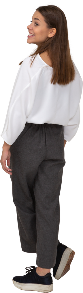 Three-quarter back view of a young lady in office clothing smiling