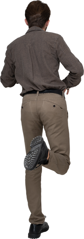 Vista traseira de um jovem com roupa de escritório levantando a perna
