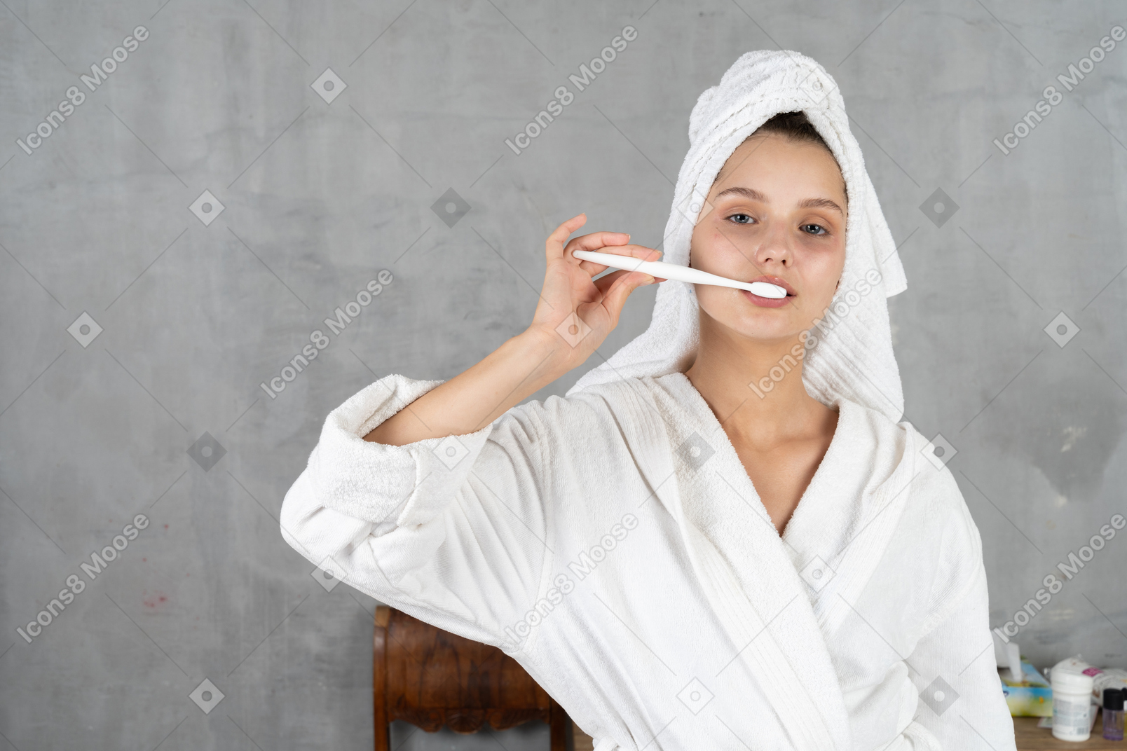 Mulher de roupão escovando os dentes