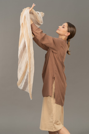 Side view of a young woman holding linen scarf