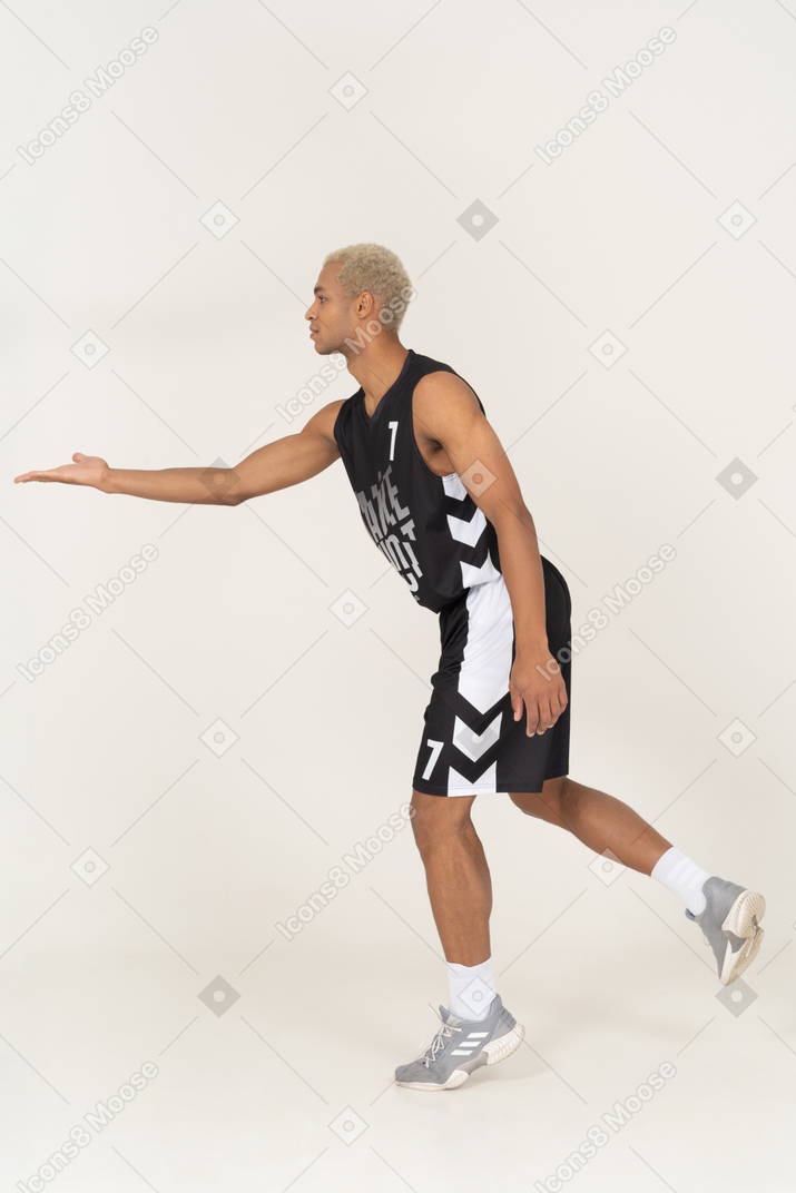 Side view of a young male basketball player outstretching hand
