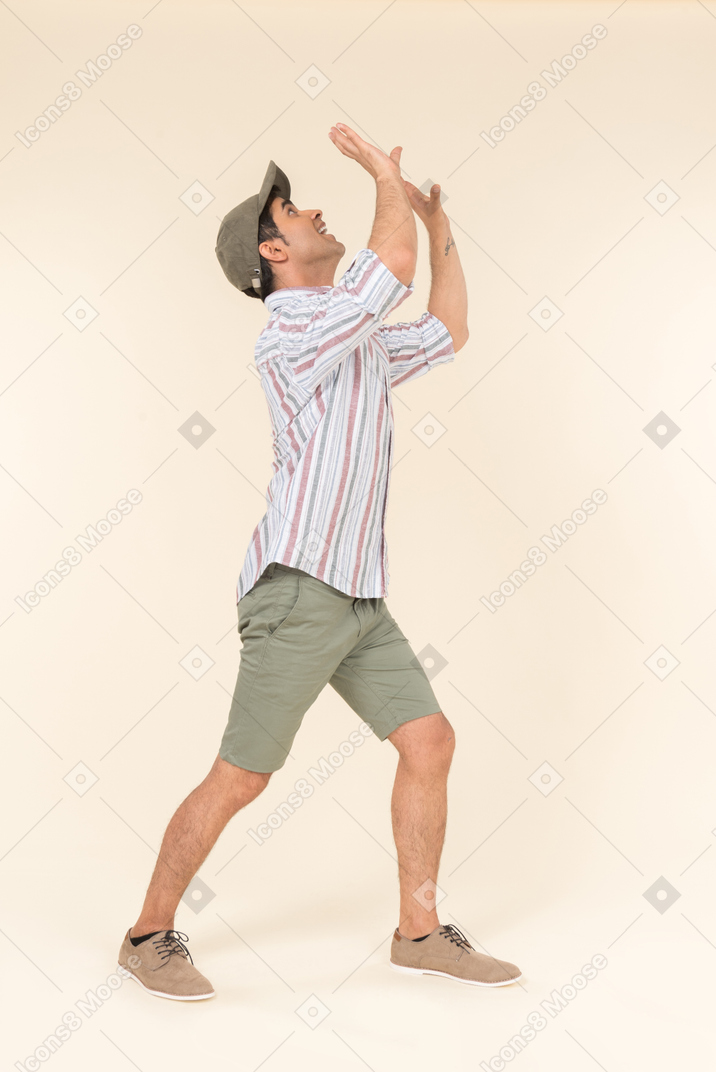 Young caucasian guy in cap standing with his hands up