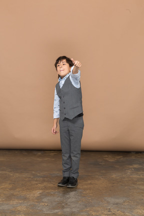 一个穿着灰色西装的可爱男孩竖起大拇指的正面图