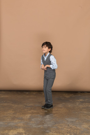Вид спереди симпатичного мальчика в сером костюме, смотрящего в камеру