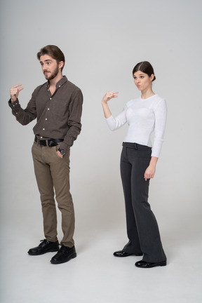 Vue de trois quarts d'un jeune couple en tenue de bureau montrant la taille de quelque chose