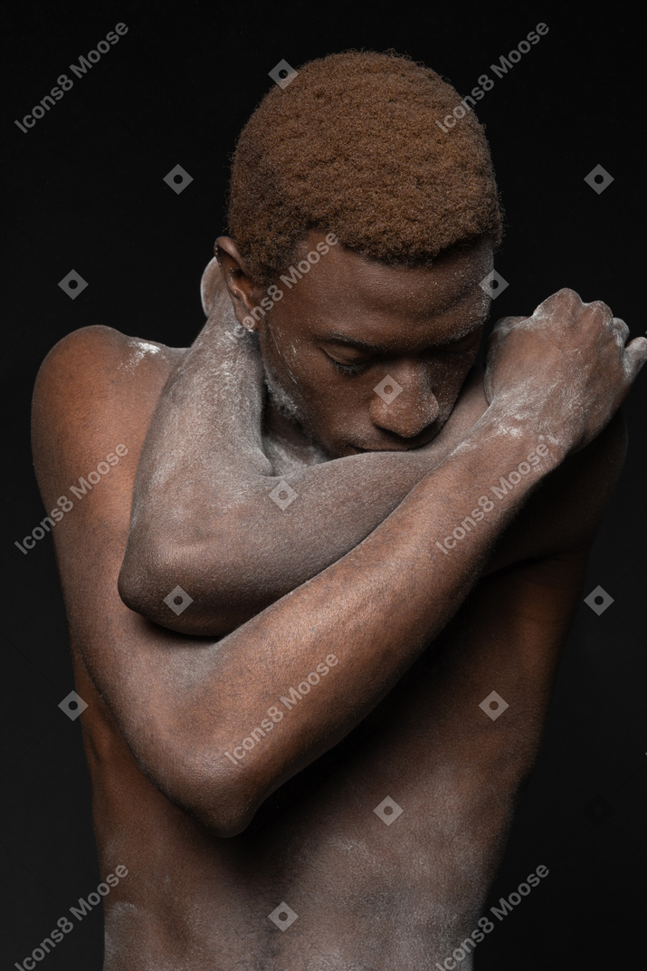 Close-up a young african manin the flour hugging himself