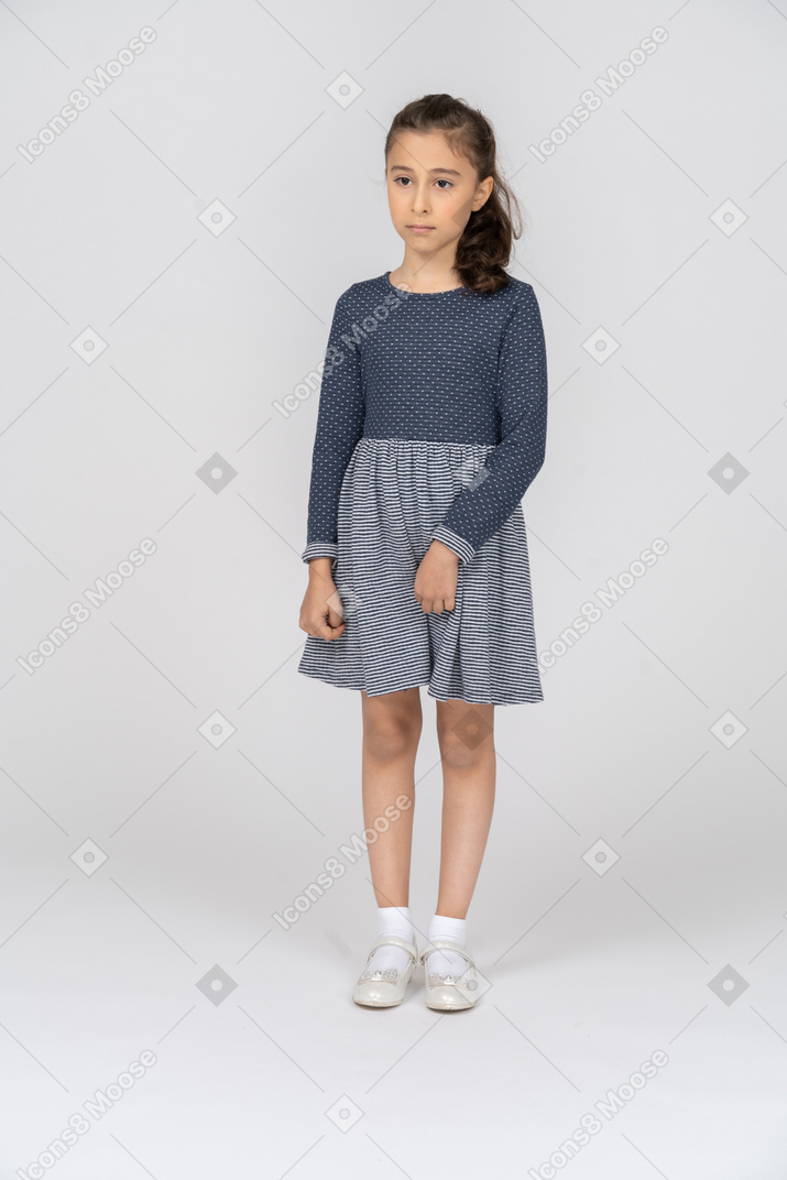 Front view of a girl fiddling with her skirt and looking sullen