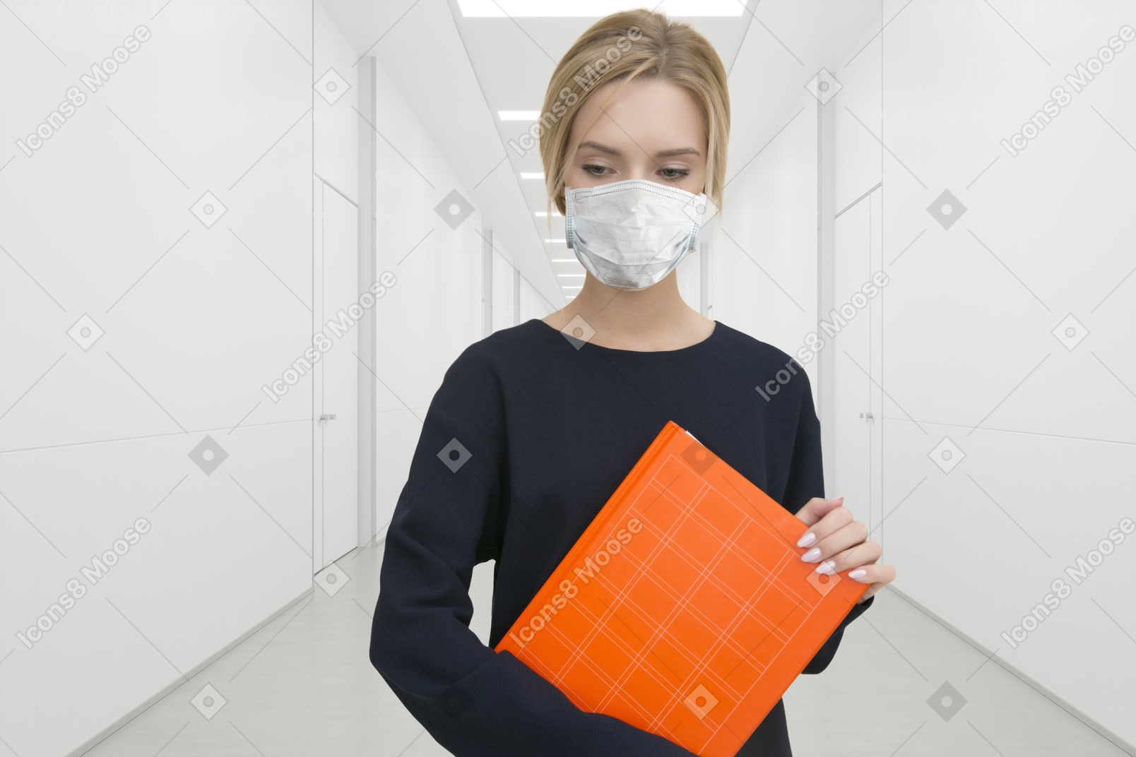 A woman wearing a face mask holding an orange folder