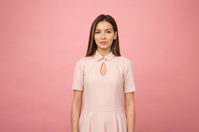 Mädchen in einem rosa kleid, das in einem rosa studio steht