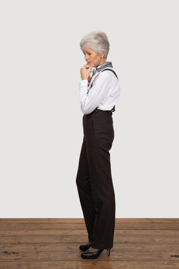 Side view of a thoughtful old lady in office clothing touching chin