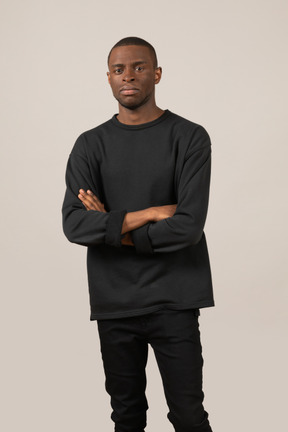 Front view of young man standing with arms crossed