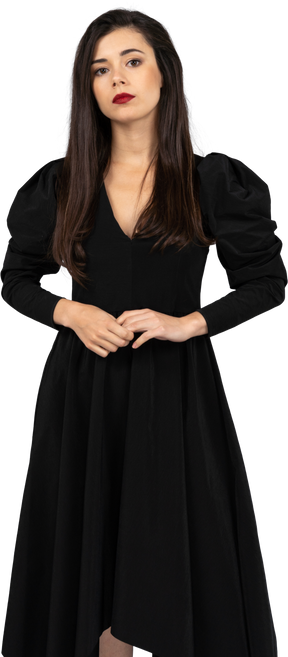 Vista frontal de uma jovem em um vestido preto parada