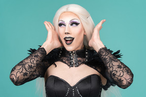 Portrait of drag queen placing happy face between hands