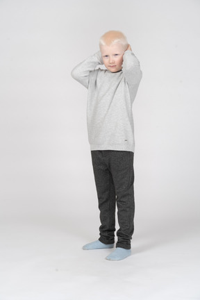 Front view of a little boy covering ears with hands