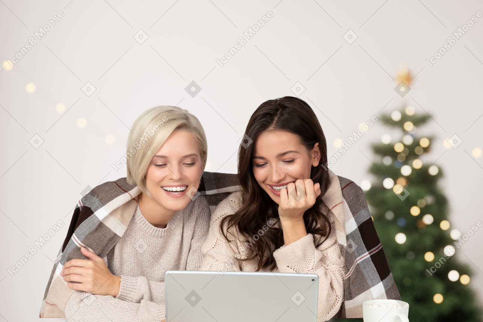 Two young women reading funny stories on laptop