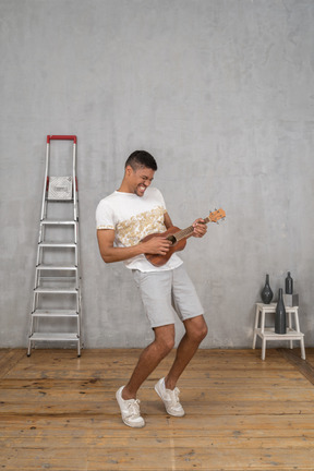 Three-quarter view of a man rocking out on ukulele standing on tiptoes