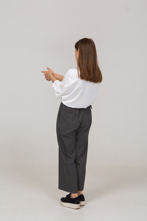 Vista traseira de três quartos de uma jovem com roupas de escritório fazendo uma foto