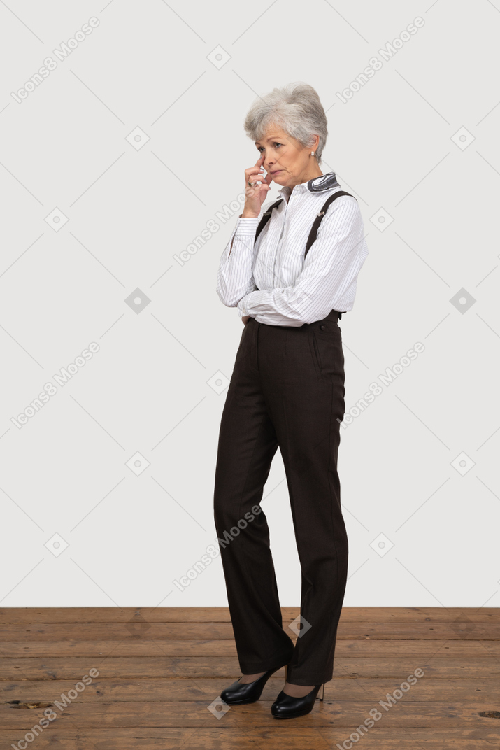 Vista de tres cuartos de una anciana pensativa en ropa de oficina tocando la cara