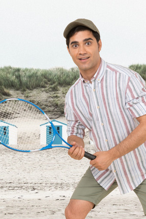 A man holding a tennis racquet on a beach