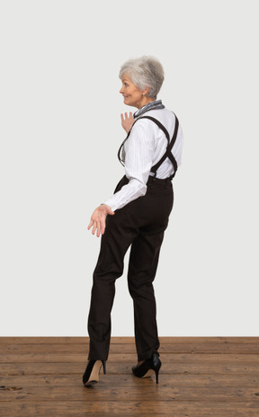 Вид сзади забавной жестикулирующей старушки в офисной одежде