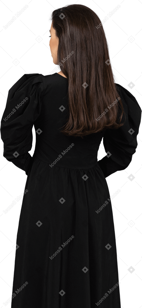 后面的观点的一位年轻的女士穿着一件黑色的连衣裙，手牵着手