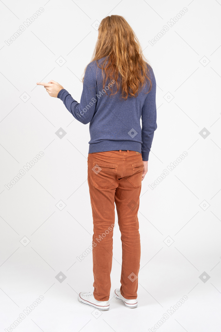 Vue arrière d'un jeune homme en vêtements décontractés pointant du doigt
