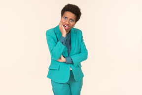 Black woman with a short haircut, wearing all blue, standing against a plain pastel background, looking emotional