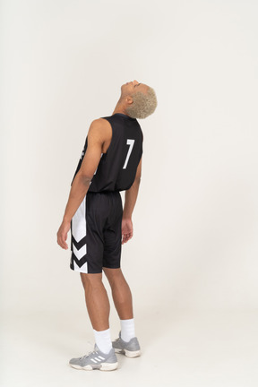 Three-quarter back view of a tired young male basketball player leaning back