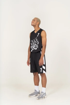 Three-quarter view of a young male basketball player raising head